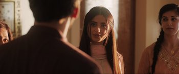 Movie still from “What's Love Got to Do with It?” (2022), directed by Shekhar Kapur – A woman with long black hair standing next to a man; Close Up shot, Over the shoulder angle