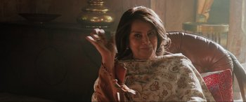 Movie still from “What's Love Got to Do with It?” (2022), directed by Shekhar Kapur – A woman is holding her hand up in the air while wearing a dress; Close Up shot, Over the shoulder angle