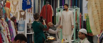 Movie still from “What's Love Got to Do with It?” (2022), directed by Shekhar Kapur – A man sitting in front of another man in a suit; Wide shot, Over the shoulder angle