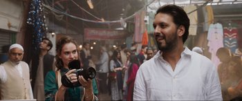 Movie still from “What's Love Got to Do with It?” (2022), directed by Shekhar Kapur – A woman taking a picture of a man with a camera; Close Up shot, Over the shoulder angle