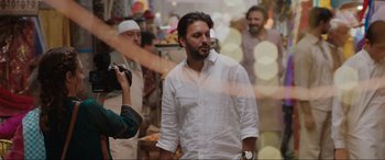 Movie still from “What's Love Got to Do with It?” (2022), directed by Shekhar Kapur – A man in a white dress shirt is taking a picture of another man; Medium shot, Over the shoulder angle