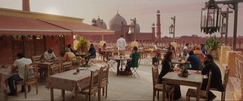 Movie still from “What's Love Got to Do with It?” (2022), directed by Shekhar Kapur – People are sitting at tables in an outdoor restaurant; Extreme Wide shot, Low angle