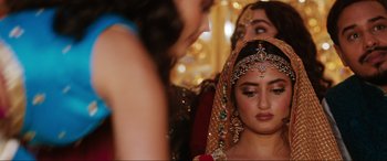 Movie still from “What's Love Got to Do with It?” (2022), directed by Shekhar Kapur – A woman in a red and gold dress with a veil on her head; Close Up shot, Over the shoulder angle