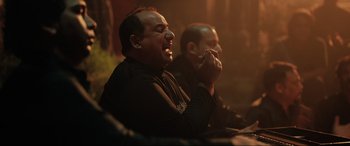 Movie still from “What's Love Got to Do with It?” (2022), directed by Shekhar Kapur – Two men sitting in front of each other and one of the men is holding his hands to his mouth; Close Up shot, Over the shoulder angle