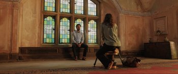 Movie still from “What's Love Got to Do with It?” (2022), directed by Shekhar Kapur – A man and a woman sitting in front of a stained glass window; Wide shot, Low angle