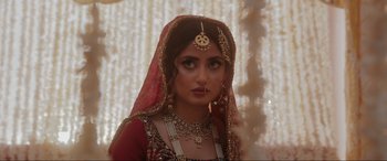 Movie still from “What's Love Got to Do with It?” (2022), directed by Shekhar Kapur – A woman in a red and gold dress with a veil; Close Up shot, Over the shoulder angle