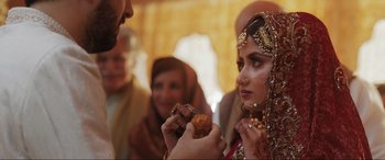 Movie still from “What's Love Got to Do with It?” (2022), directed by Shekhar Kapur – A woman is holding a piece of food in front of a man; Extreme Close Up shot, Over the shoulder angle