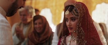 Movie still from “What's Love Got to Do with It?” (2022), directed by Shekhar Kapur – A woman in a red dress and a gold headpiece; Close Up shot, Over the shoulder angle