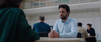 Movie still from “What's Love Got to Do with It?” (2022), directed by Shekhar Kapur – A man sitting in front of another man at a table; Medium shot, Over the shoulder angle