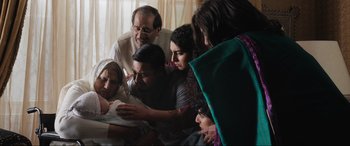 Movie still from “What's Love Got to Do with It?” (2022), directed by Shekhar Kapur – A group of people gathered around a baby; Medium shot, High angle