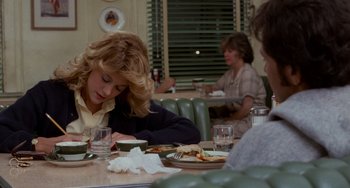 Movie still from “When Harry Met Sally...” (1989), directed by Rob Reiner – A woman sitting at a table in front of a plate of food; Medium shot, Over the shoulder angle