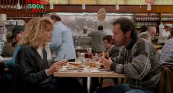 Movie still from “When Harry Met Sally...” (1989), directed by Rob Reiner – A man and a woman sitting at a table in front of a plate of food; Medium shot, Over the shoulder angle