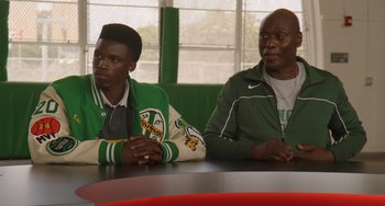 Movie still from “White Men Can't Jump” (2023), directed by Calmatic – Two men are sitting at a table in front of each other; Medium shot, Over the shoulder angle
