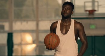 Movie still from “White Men Can't Jump” (2023), directed by Calmatic – A man holding a basketball on a basketball court; Medium shot, Over the shoulder angle