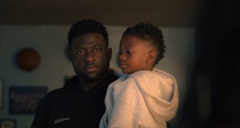 Movie still from “White Men Can't Jump” (2023), directed by Calmatic – A man and a child are standing together; Close Up shot, Over the shoulder angle