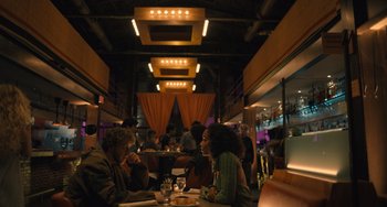 Movie still from “White Men Can't Jump” (2023), directed by Calmatic – Two people are sitting at a table in a restaurant; Wide shot, Low angle