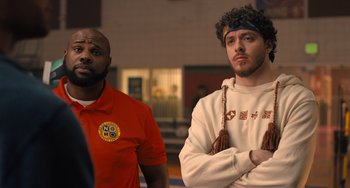 Movie still from “White Men Can't Jump” (2023), directed by Calmatic – Two men standing next to each other in front of a wall; Medium shot, Over the shoulder angle