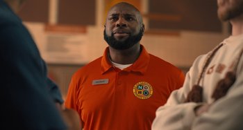 Movie still from “White Men Can't Jump” (2023), directed by Calmatic – A man in an orange shirt is looking up; Close Up shot, Low angle