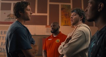 Movie still from “White Men Can't Jump” (2023), directed by Calmatic – A group of men standing next to each other in a room; Medium shot, Over the shoulder angle