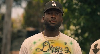 Movie still from “White Men Can't Jump” (2023), directed by Calmatic – A man in a baseball cap and a t - shirt; Close Up shot, Over the shoulder angle