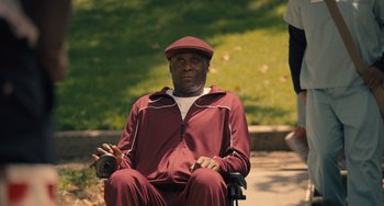 Movie still from “White Men Can't Jump” (2023), directed by Calmatic – An older man sitting in a wheel chair in a park; Medium shot, High angle