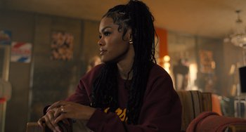 Movie still from “White Men Can't Jump” (2023), directed by Calmatic – A woman with dreadlocks sitting on a couch; Close Up shot, Over the shoulder angle