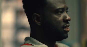 Movie still from “White Men Can't Jump” (2023), directed by Calmatic – A man's face in a dark room; Close Up shot, Over the shoulder angle