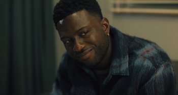 Movie still from “White Men Can't Jump” (2023), directed by Calmatic – A person smiling for the camera; Close Up shot, Over the shoulder angle