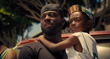 Movie still from “White Men Can't Jump” (2023), directed by Calmatic – A man and a boy are posing for a picture; Close Up shot, Low angle