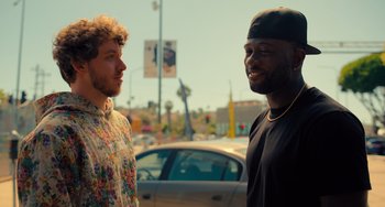 Movie still from “White Men Can't Jump” (2023), directed by Calmatic – Two men standing next to each other on the street; Medium shot, Over the shoulder angle