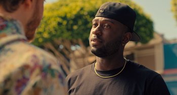 Movie still from “White Men Can't Jump” (2023), directed by Calmatic – A person wearing a hat; Close Up shot, Over the shoulder angle