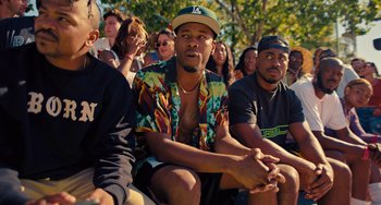 Movie still from “White Men Can't Jump” (2023), directed by Calmatic – A group of people sitting in a crowd watching something; Medium shot, Over the shoulder angle