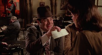 Movie still from “Who Framed Roger Rabbit” (1988), directed by Robert Zemeckis – A man in a hat is holding up a piece of paper; Close Up shot, Over the shoulder angle