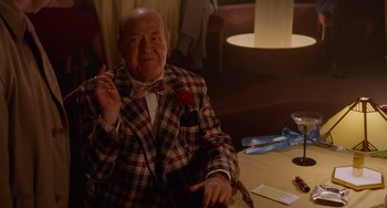 Movie still from “Who Framed Roger Rabbit” (1988), directed by Robert Zemeckis – An older man sitting at a table with a cigarette in his hand; Medium shot, Over the shoulder angle