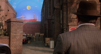 Movie still from “Who Framed Roger Rabbit” (1988), directed by Robert Zemeckis – A man wearing a suit and tie standing in front of a brick building; Extreme Wide shot, Over the shoulder angle