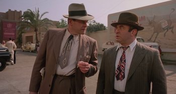 Movie still from “Who Framed Roger Rabbit” (1988), directed by Robert Zemeckis – Two men in suits and hats are standing outside; Medium shot, Over the shoulder angle