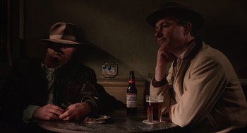 Movie still from “Who Framed Roger Rabbit” (1988), directed by Robert Zemeckis – Two men sitting at a table with a bottle of beer; Medium shot, High angle