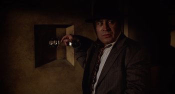 Movie still from “Who Framed Roger Rabbit” (1988), directed by Robert Zemeckis – A man in a suit and tie holding a camera; Medium shot, Low angle