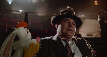 Movie still from “Who Framed Roger Rabbit” (1988), directed by Robert Zemeckis – A man wearing a suit and tie holding a cartoon; Medium shot, Low angle