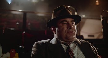 Movie still from “Who Framed Roger Rabbit” (1988), directed by Robert Zemeckis – A man wearing a suit and a hat is sitting in a chair; Close Up shot, Low angle