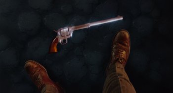 Movie still from “Who Framed Roger Rabbit” (1988), directed by Robert Zemeckis – A man standing in front of a gun with a light shining on it; Extreme Close Up shot, Overhead angle