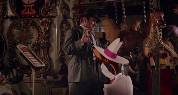 Movie still from “Who Framed Roger Rabbit” (1988), directed by Robert Zemeckis – A man in a suit and hat standing in front of a carousel; Medium shot, Over the shoulder angle