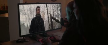 Movie still from “Wifelike” (2022), directed by James Bird – A man sitting in front of a computer monitor; Wide shot, Over the shoulder angle