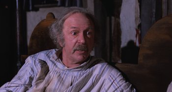Movie still from “Willy Wonka & the Chocolate Factory” (1971), directed by Mel Stuart – An older man with a mustache sitting in a chair; Close Up shot, Low angle