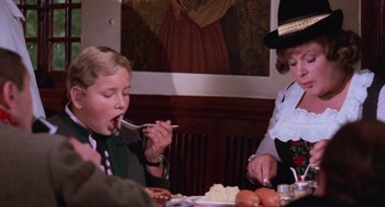 Movie still from “Willy Wonka & the Chocolate Factory” (1971), directed by Mel Stuart – A woman and a child eating food at a table; Medium shot, Over the shoulder angle