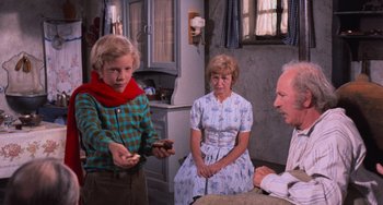 Movie still from “Willy Wonka & the Chocolate Factory” (1971), directed by Mel Stuart – A young boy holding a piece of cake in front of an older woman and older man; Medium shot, Over the shoulder angle
