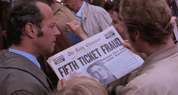 Movie still from “Willy Wonka & the Chocolate Factory” (1971), directed by Mel Stuart – A man holding a newspaper with a picture of a man on it; Close Up shot, Over the shoulder angle