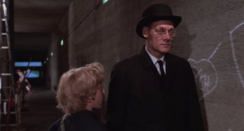 Movie still from “Willy Wonka & the Chocolate Factory” (1971), directed by Mel Stuart – A man in a hat and glasses and a boy in a suit; Medium shot, Over the shoulder angle