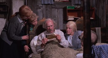 Movie still from “Willy Wonka & the Chocolate Factory” (1971), directed by Mel Stuart – An old man sitting in a chair holding a piece of paper; Medium shot, High angle