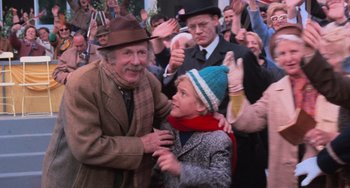 Movie still from “Willy Wonka & the Chocolate Factory” (1971), directed by Mel Stuart – An old man and a little girl in a crowd of people; Medium shot, Over the shoulder angle
